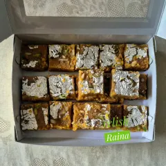 A box of my traditional Moong Daal Barfi, decorated with pure silver vark. I slow-roast the lentils in pure ghee for hours to achieve the perfect golden-brown color and rich, decadent flavor that melts in your mouth.
