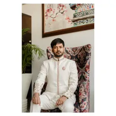 The groom seated in a regal, high-backed chair. This posed shot exudes confidence and style, highlighting the fine embroidery on his outfit.