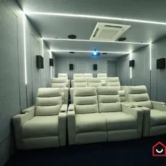 A stunning example of a modern home cinema in Madurai, featuring clean lines and a cool color palette. The bright white recliners contrast beautifully with the grey acoustic-paneled walls and blue carpet, while integrated LED strips provide a futuristic ambiance.