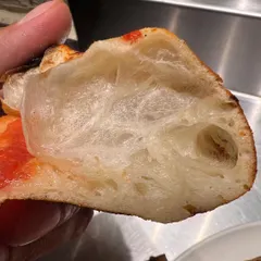 A cross-section of our dough after it's been baked. Look at that open, airy structure. This is the result of a long fermentation process and is the secret to our light, digestible crust.
