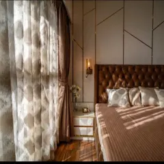 The play of natural light can transform a room. Here, sunlight streams through sheer curtains, highlighting the textures of the bedding and the geometric pattern on the accent wall, creating a serene and peaceful morning ambiance.