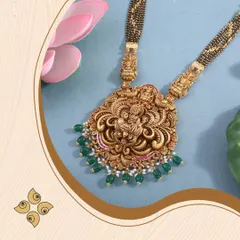 A close-up of a magnificent temple jewellery pendant on a mangalsutra chain. The detailed carving of the deity, surrounded by green beads, makes this a unique fusion piece that appeals to modern women who cherish tradition.