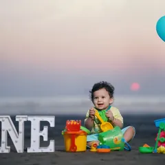 A happy first birthday shoot on the beach at sunset. Using 'ONE' block letters and colorful toys, I create a playful and scenic memory of this important milestone.