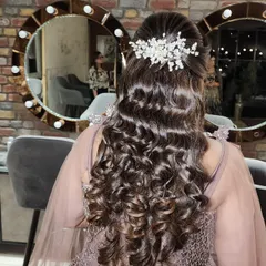 The details matter. This hairstyle combines soft curls with a beautifully placed hairpiece, creating an elegant and romantic look for any special occasion.