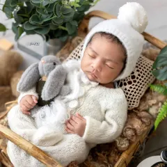 The little pom-pom hat just adds to the cuteness. This close-up shot highlights the delicate features of a newborn, from their soft skin to their tiny hands, all while they dream away.