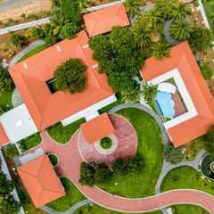 This top-down view showcases the project's core architectural forms, including the main residence with its central courtyard and the separate clubhouse enclosing the swimming pool, all unified by terracotta-tiled roofs.