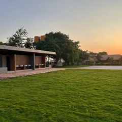 A wide expanse of freshly laid lawn for a commercial property at sunset. I ensure proper soil preparation and use high-quality turf for a durable, vibrant green space that can handle foot traffic.