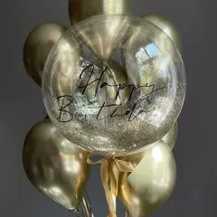 A glittering gold birthday bunch. This arrangement combines chrome gold balloons with a transparent bubble balloon filled with gold glitter and customized with "Happy Birthday" script.