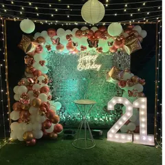 A close-up of the terrace birthday decoration, focusing on the shimmer wall. The wall reflects the light beautifully, creating a dynamic background for the balloon arch and marquee numbers.