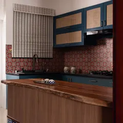 A view of the South Indian-inspired kitchen, showing the live-edge wood island countertop and the colorful tile inlay. The space is a blend of bold color, natural materials, and traditional patterns.