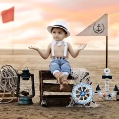 An outdoor sailor-themed shoot on a real beach at sunset. The beautiful light and authentic props like an anchor and lantern create a stunning and adventurous portrait.
