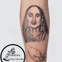 This portrait tattoo honors a mother's memory, with a second design below of a hand holding a child's finger. It's a powerful combination of realism and symbolism.