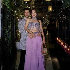 A happy client couple at a festive event. He is wearing a custom-printed Indo-Western jacket, perfectly coordinated for a celebratory night.