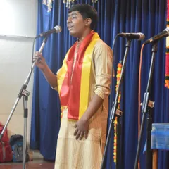 A student vocalist sings with passion during our Kannada Rajyotsava celebration. He wears the traditional yellow and red sash to honor the occasion.