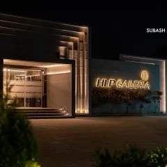 The entrance of HLP Galleria, showcasing an intricate play of recessed and protruding volumes. The strategic use of concealed lighting accentuates the geometric facade, creating a dynamic and inviting entry point even after dark.