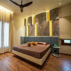 The son's bedroom in the "Vertical Nest" project, featuring a backlit stone-paneled wall and a comfortable bed that even the family dog, Leo, loves.