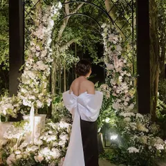For a glamorous bachelorette, we designed a Chanel-inspired welcome dinner. This moment captures the chic elegance of the event, with a custom gown echoing the dramatic floral arch, blending high fashion with our bespoke floral artistry.