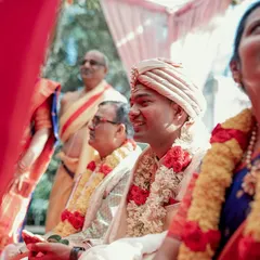 The groom, dressed in traditional attire, smiles during the wedding rituals, with his family looking on. We document the key moments for both the bride and groom throughout the day.
