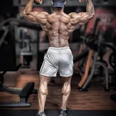 This is the back that was rebuilt. Every muscle fiber you see was earned through years of careful, intense training post-injury. This rear double bicep pose shows the detail and thickness that is possible even after significant setbacks.