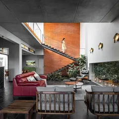 This wide view of the living room shows how we use different elements to define the space. The Cuddapah stone flooring with brass inlays guides movement, while the indoor greenery and large windows ensure the home feels connected to nature from every angle.