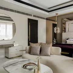 A view of the master bedroom's lounge and vanity area. The round mirror and fluted dressing table complement the room's curves, while the deep plum and neutral tones create a sophisticated and restful palette.