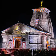 A clear, stunning night shot of the Kedarnath Temple, fully lit and standing majestically against the dark Himalayan peaks. This image showcases the temple's intricate architecture and its powerful presence.