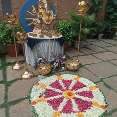 A traditional setup featuring a Ganesha idol, lotus-shaped brass lamps, and a colorful flower rangoli. This type of decor is perfect for inaugurations and festive corporate celebrations.