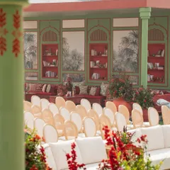 Guest seating with a view of the lounge area. The color palette of red, green, and cream is consistently used across all elements to create a cohesive and immersive experience.