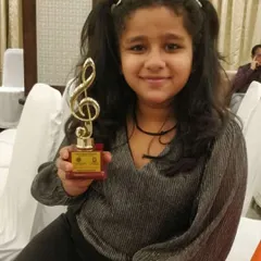 Student Kavya Saraf with her trophy after winning a competition at the Lions Club. We coach our students for competitive events, helping them gain confidence and recognition.