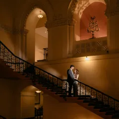 I love playing with light and architecture to create portraits that feel like art. Here, the grandeur of the staircase and the soft lighting frame the couple in a classic, romantic moment.