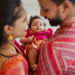 An intimate, over-the-shoulder shot showing the baby looking up at her loving parents. This perspective creates a feeling of warmth and connection, documenting the bond of a new family.