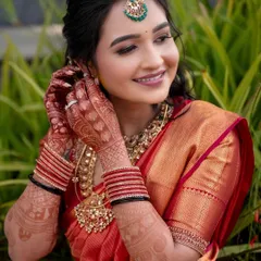 A bride dressed for her Varapooja ceremony in a classic red and gold Kanchipuram saree. The simple, elegant embroidery on her blouse complements the richness of the silk and antique jewelry.