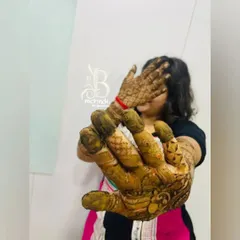 The moment of truth. A client playfully shows off her hands after the henna paste has been applied, waiting for that beautiful dark stain to appear.