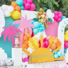 Bring on the summer vibes with a bright and tropical party theme. This incredibly colorful outdoor setup is bursting with energy, featuring hot pink palm trees, a cheerful sun cutout, and balloons in every color of the rainbow.