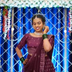 A happy guest posing for a photo. The background shows the detailed decor, including a blue draped curtain with a white geometric lattice and hanging floral strings.