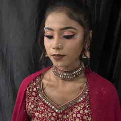 A creative airbrush makeup look featuring decorative pearl bindis and sharp, graphic eyeliner. This demonstrates how airbrush techniques can be used for both a flawless base and artistic details.