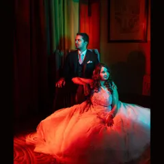 A regal portrait of the couple seated, bathed in dramatic red and green light for a cinematic reception look.