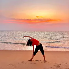 Performing the triangle pose, Trikonasana, against a stunning sunset on the beach. The golden hour light and the sound of the waves make for an unforgettable practice.