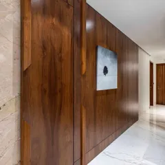 Luxury and style define this grand passage in a 4-bedroom Mumbai house. The centerpiece is a stunning 10-foot-wide sliding door, draped in rich veneer that exudes mid-century modern charm with a contemporary twist.