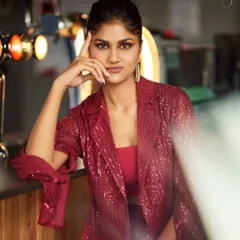 A close-up portrait of a model wearing the red sequined jacket. The shot highlights the sparkle of the fabric and the sharp cut of the lapels.
