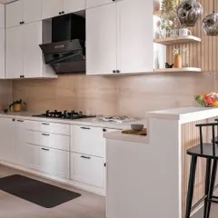 Another angle of the white kitchen, showing the breakfast bar with black stools and open shelving for decor. The design is perfect for small spaces, making the kitchen feel open and airy.
