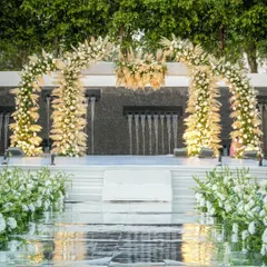 For a 25th anniversary, we created this ethereal sundowner celebration over water. The all-white floral arch against the cascading waterfall backdrop speaks of timeless elegance and enduring love, making for a truly exquisite milestone.