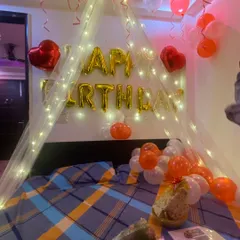 Another angle of the fairy light cabana setup. You can see how the warm lights and balloons work together to create a dreamy and romantic ambiance for a birthday surprise. A bouquet of flowers on the bed adds a finishing touch.