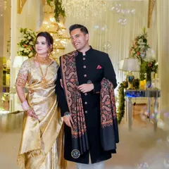 A beautiful couple makes their entrance at a reception filled with ethereal smoke and bubbles. The bride's gold saree and the groom's classic bandhgala perfectly match the elegant decor.