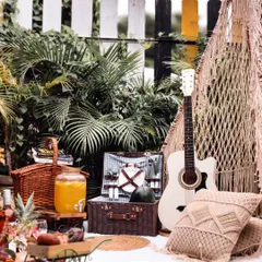Let's turn your backyard into a bohemian dream. This picnic setup features a macrame teepee, plush cushions, and a guitar for a relaxed, musical vibe, perfect for a casual get-together or celebration.