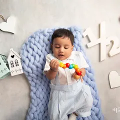 Celebrating a half-birthday milestone. This flat-lay style photo shows the baby on a soft blue blanket, surrounded by props that mark his six-month celebration.