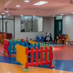 A safe and engaging play area designed for toddlers. The space is enclosed with colorful fencing and filled with soft toys and age-appropriate equipment, allowing for free play under supervision.