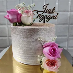 An elegant engagement cake to celebrate a special commitment. This cake is finished with a sparkling shimmer and adorned with fresh pink roses and baby's breath.