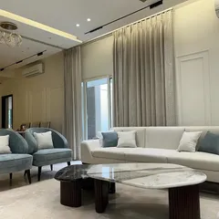 The addition of plush blue accent chairs introduces a gentle touch of color to the neutral palette, enhancing the room's sophisticated character.