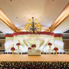 We specialize in creating opulent reception stages that serve as the magnificent centerpiece of your celebration. This design features a grand floral canopy of red and white roses with cascading crystal elements.
